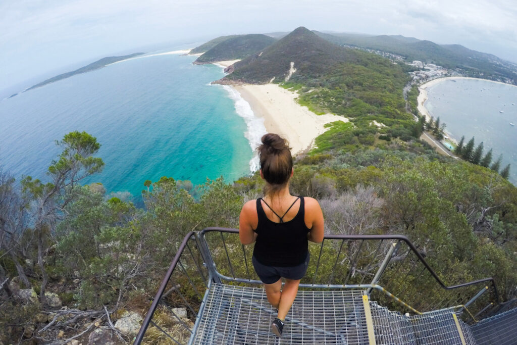 Woman looking at the panoramic landscape view of Zenith Beach at the top of Tomaree Head Summit Walk
